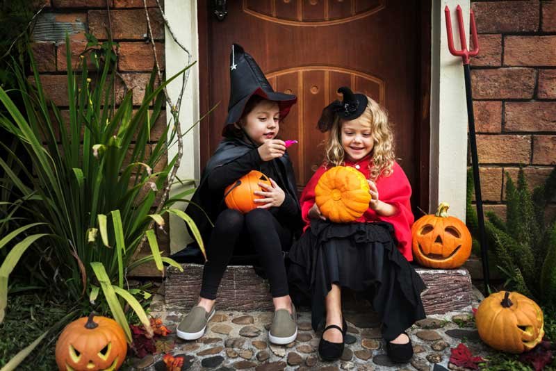 Dos niñas disfrazadas en el día del Halloween sentadas mirando los dulces que les dieron.