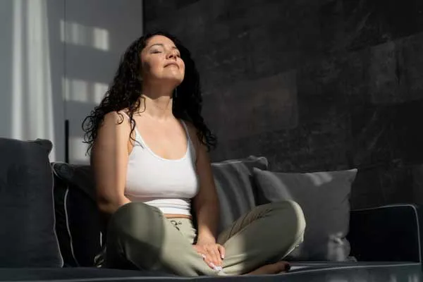 Una mujer con los ojos cerrados practicando la respiración. 