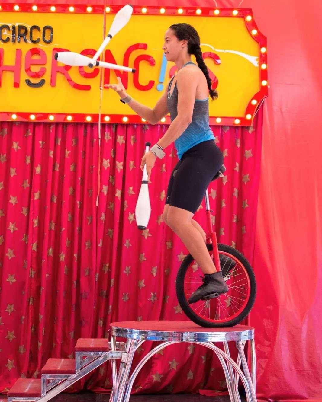 Una joven malabarista del Circus Herencia monta un monociclo