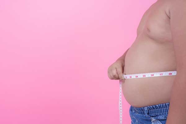 Un hombre con obesidad mide su abdomen con un metro.