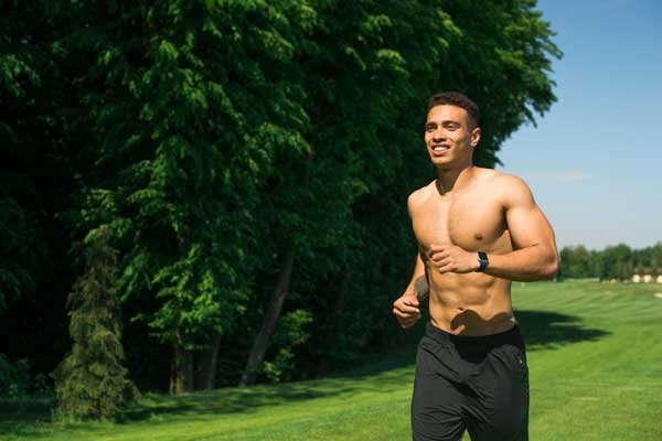 Hombre joven sonriente corriendo en un campo abierto