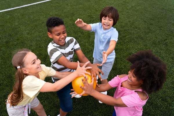 Cuatro niños jugando con un balón en una cancha sintética.
