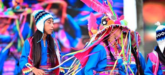 Jóvenes indígenas vestidos con sus trajes típicos, bailando durante la celebración del Inti Raymi o Fiesta del Sol